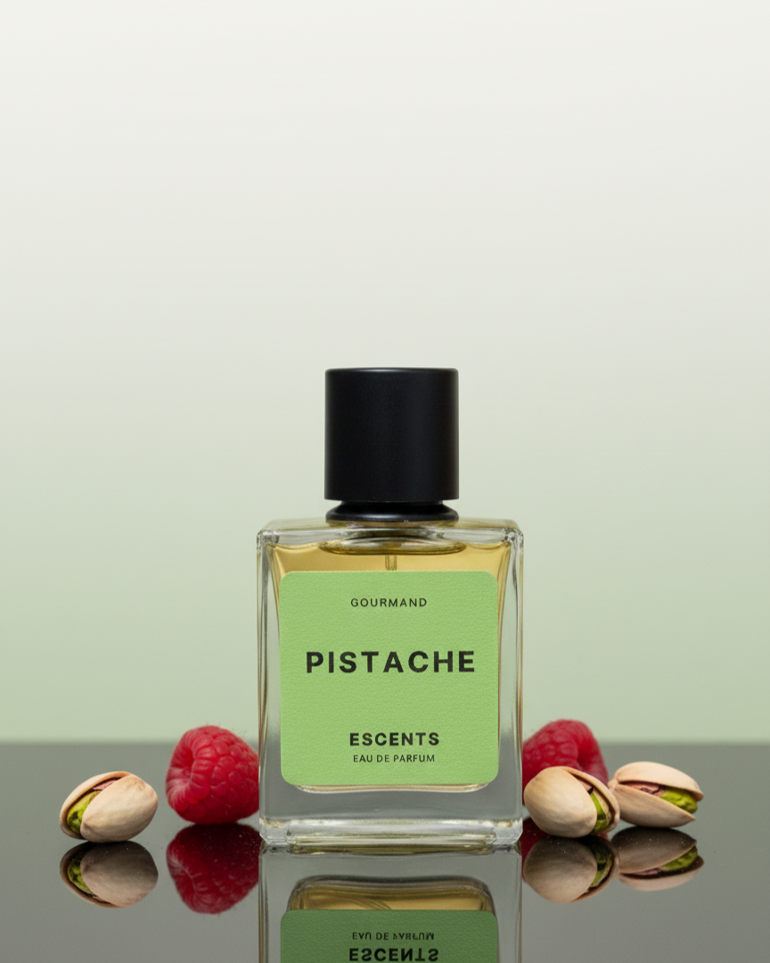Perfume bottle labeled 'Pistache' with pistachios and raspberries on a reflective surface.